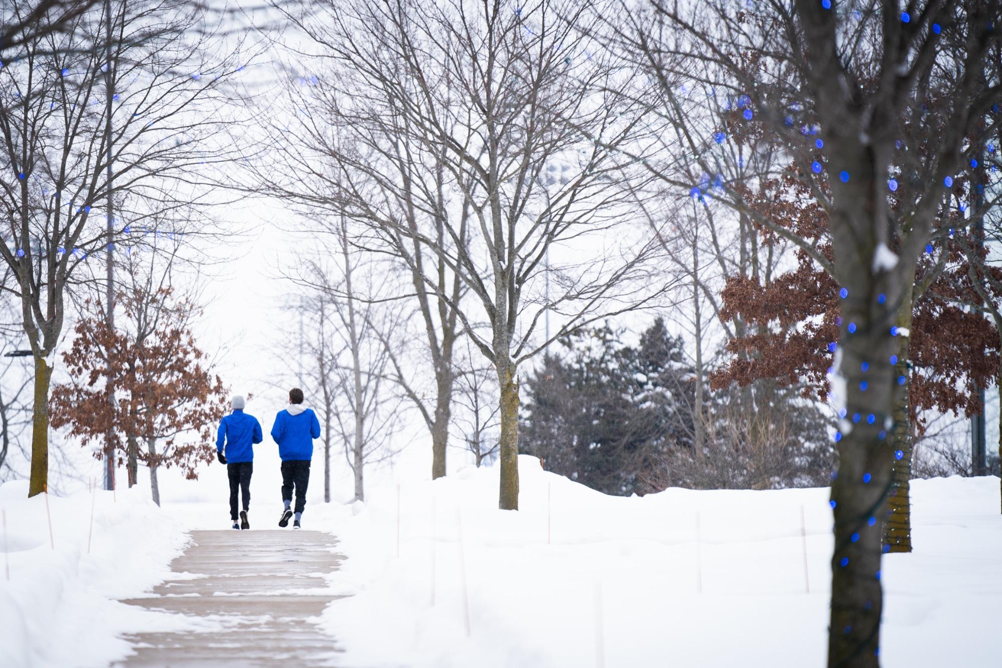 students running on campus on a snowy day